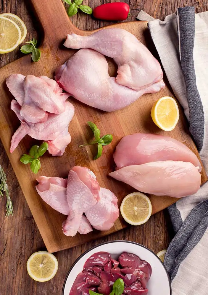 Hand-cut chicken breast, wings and leg quarters on a wooden board
